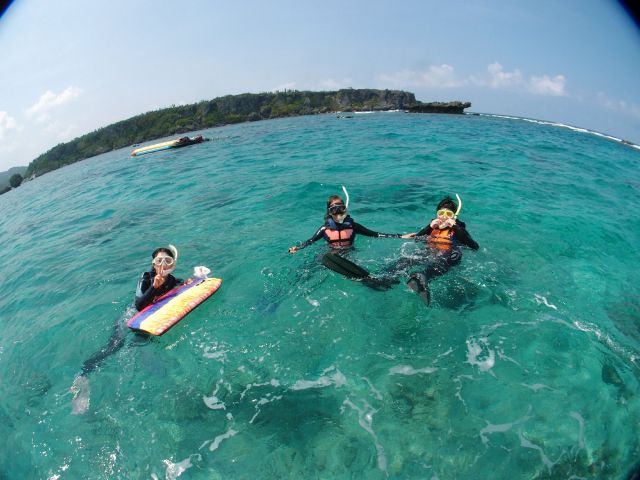 沖縄の海で家族三世代がボートからシュノーケリングを楽しんでいる様子