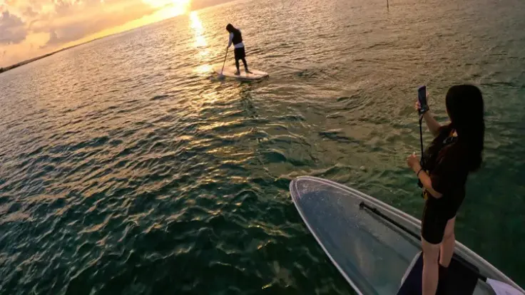 沖縄の海で夕日を眺めながらサンセットSUPを楽しむ様子