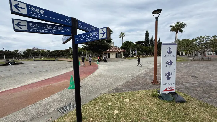 奥武山公園の園路に立つ『おき宮』の案内看板。矢印で進む方向が示されている。