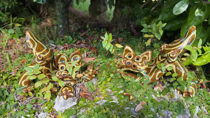 やちむんの里の石垣の上に置かれたシーサーの置物。素朴で愛嬌があり、散策中にほっとする雰囲気を演出する