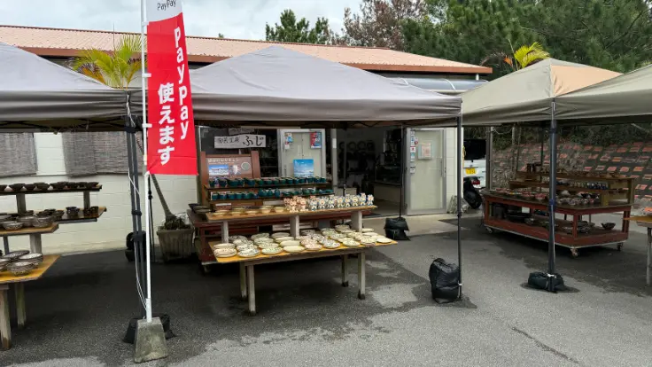 陶芸工房ふじの店先に、色柄が楽しいやちむんが並んでいる様子