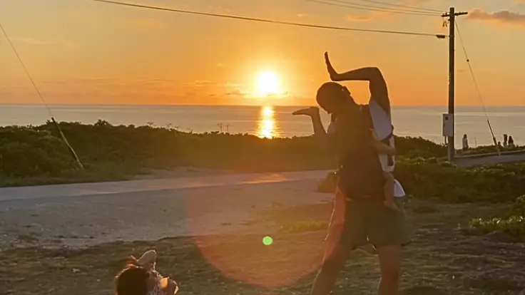 夕日を背景に、残波岬の海辺でシルエットになって立つ人