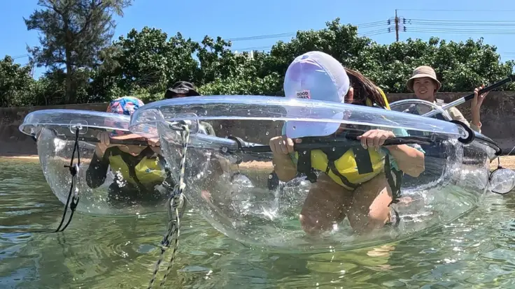 沖縄・恩納村の透明度の高い海でクリアカヤックを体験している様子。カヤックの底が透明で海の中が見えるイメージ