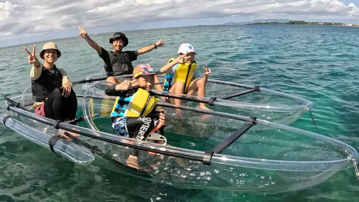 沖縄・恩納村の透明度の高い海でクリアカヤックを体験している様子。水の上から海の中が見えるイメージ