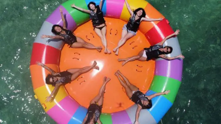 沖縄の海でみんなでチューブ系マリンスポーツを楽しんでいる様子。複数人で一緒に盛り上がれる体験イメージ。