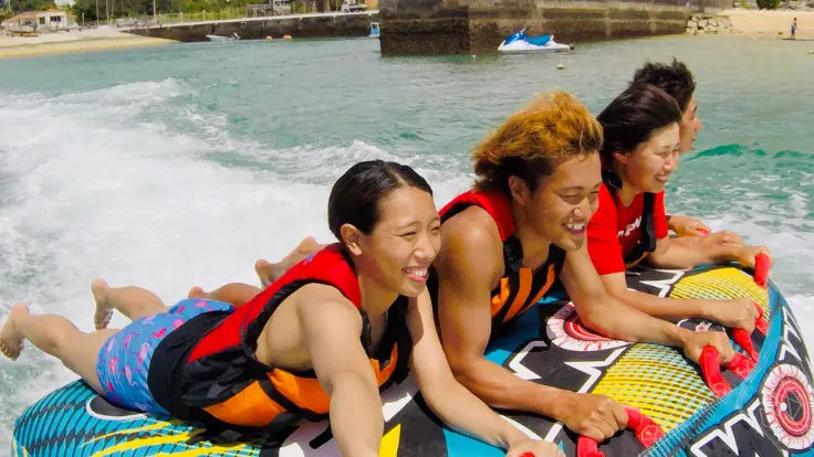 沖縄の海でスリラー系のマリンスポーツを楽しんでいる様子。水面近くを走るスピード感のある体験イメージ。