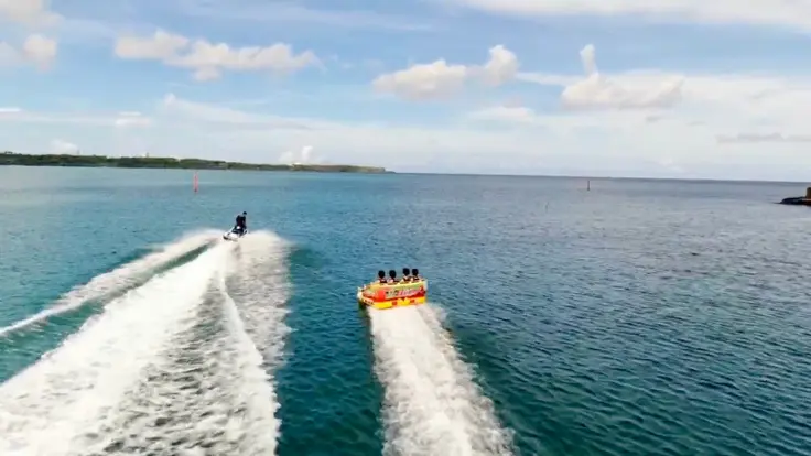 沖縄の海でチューブ系マリンスポーツを楽しんでいる様子。海の上でみんなで遊べる体験イメージ。
