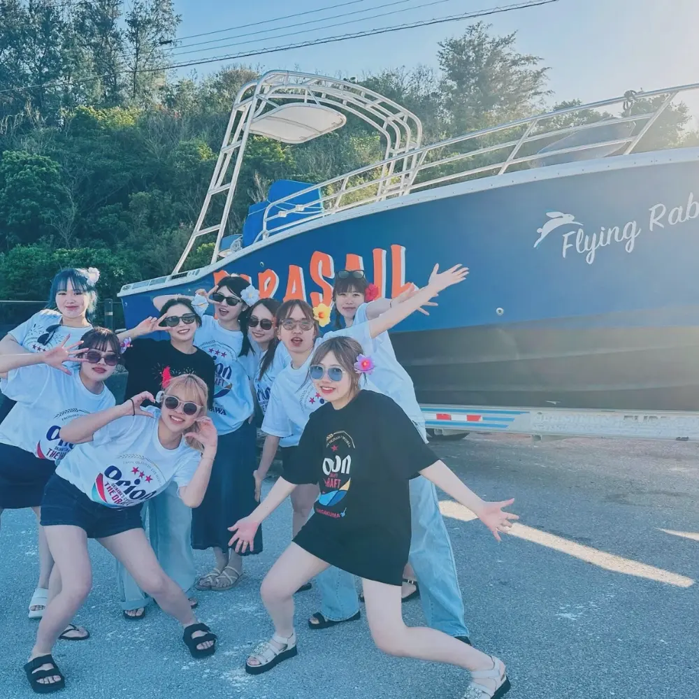 パラセールボートの前で、学生グループが記念撮影をしている様子