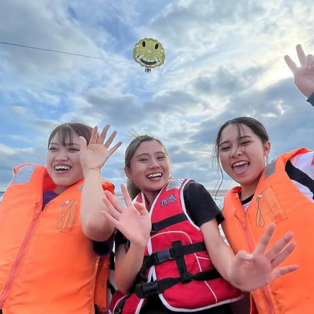 パラセール体験中のフライトを背景に、参加者が記念撮影している様子